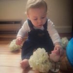 baby sitting on floor with flowers