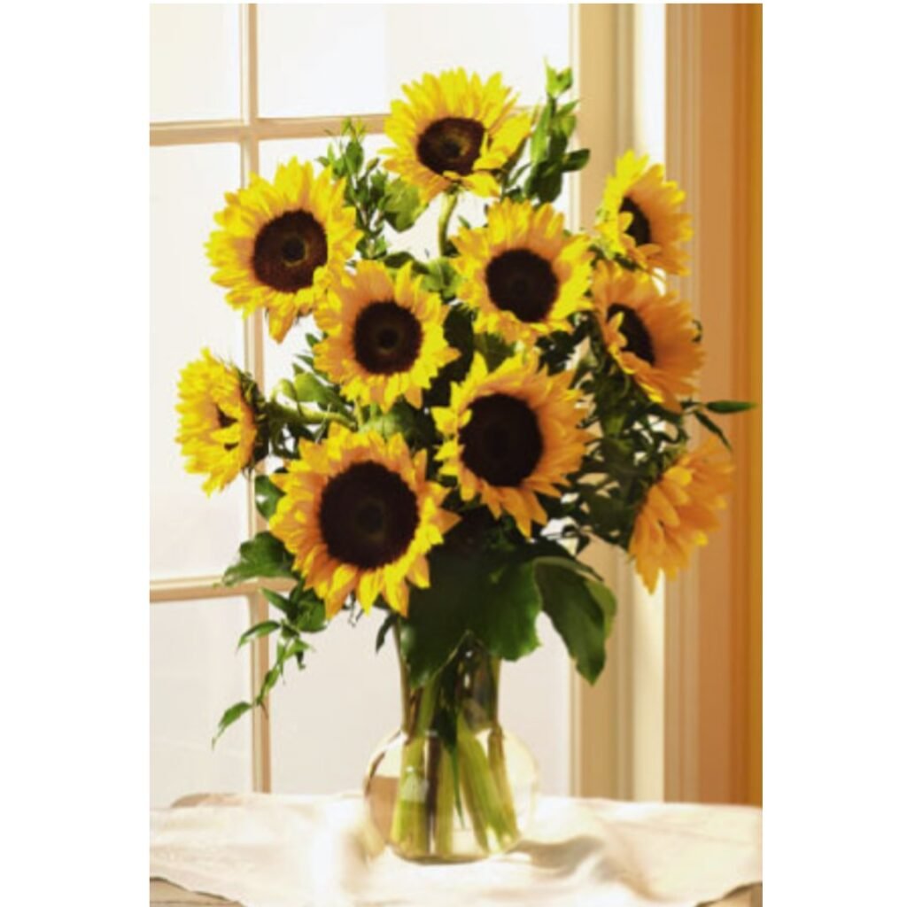 Sunflowers in a vase sitting on a table in front of a window