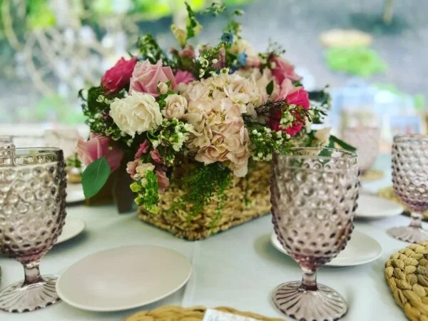 Flowers in a basket sitting on a table with china